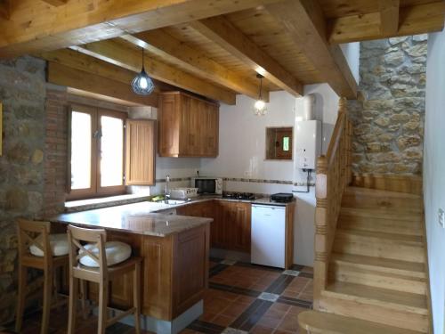 a kitchen with wooden cabinets and a stone wall at Casa de Aldea La Xunta in Cangas de Onís