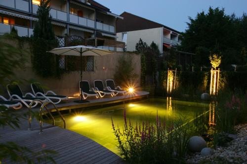 a pool with chairs and an umbrella next to a building at Wunsch Hotel Mürz - Natural Health & Spa Hotel in Bad Füssing