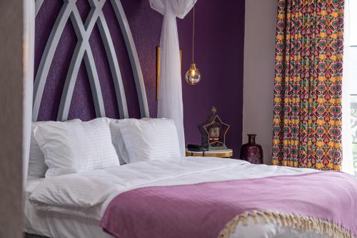 a bedroom with a large white bed with purple walls at Hotel Karbel Sun in Oludeniz