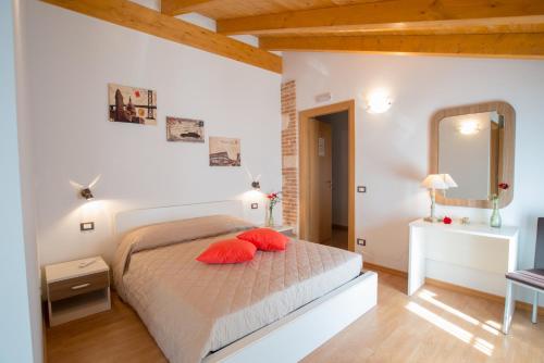 ArcugnanoにあるBed and Breakfast La Quieteのベッドルーム1室(赤い枕と鏡付きのベッド1台付)