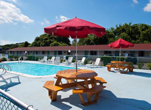 a picnic table with an umbrella next to a pool at Economy Motel Inn and Suites Somers Point in Somers Point