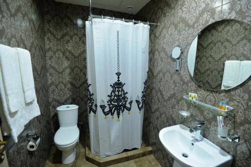uma casa de banho com uma cortina de chuveiro, um WC e um lavatório. em Yerevan Deluxe Hotel em Yerevan