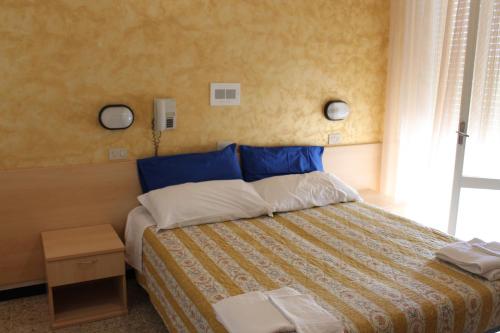 una camera da letto con un letto con lenzuola blu e bianche e una finestra di Hotel Loretta a Rimini