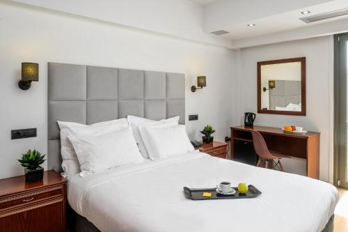 a hotel room with a bed, desk, and nightstand at Athens Odeon Hotel in Athens