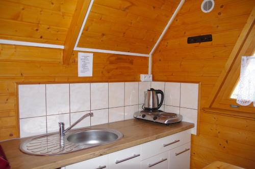a kitchen with a sink in a wooden cabin at Ośrodek Wczasowy Słoneczko in Dźwirzyno