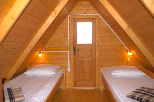 two beds in a attic room with a door at Ośrodek Wczasowy Słoneczko in Dźwirzyno