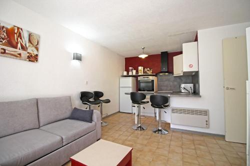 een woonkamer met een bank en een keuken bij Le Vallon des Sources in Digne-les-Bains