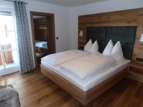 a bedroom with a large white bed with a wooden headboard at Wellness Ferienwohnungen Zellertalblick in Drachselsried