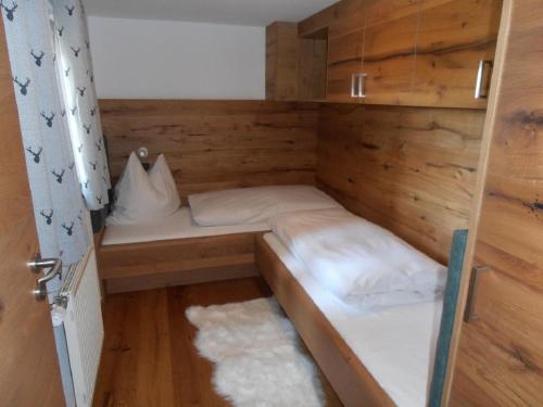 a small bed in a wooden room with a door at Wellness Ferienwohnungen Zellertalblick in Drachselsried