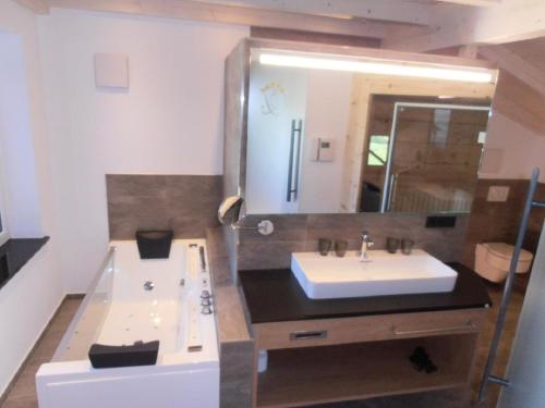 a bathroom with a sink and a tub and a mirror at Wellness Ferienwohnungen Zellertalblick in Drachselsried