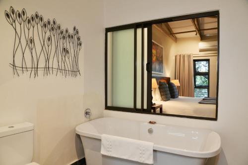 a bathroom with a large mirror above a bath tub at Bushveld Terrace Safari Hotel, Lodge & Spa in Phalaborwa