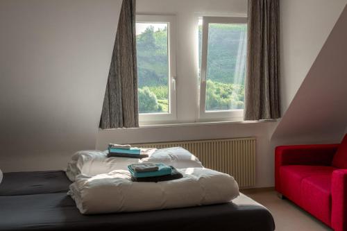 een kamer met 2 bedden en een rode stoel bij Ferienhaus am Kloster Stuben in Bremm