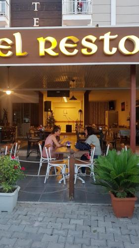 two men sitting at a table outside of a restaurant at Neoss Boutique Hotel in Siğacık