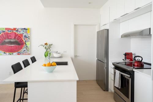 a white kitchen with a white counter top and a sink at Le Se7t Penthouses in Montréal