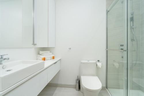 a white bathroom with a toilet and a glass shower at Le Se7t Penthouses in Montréal