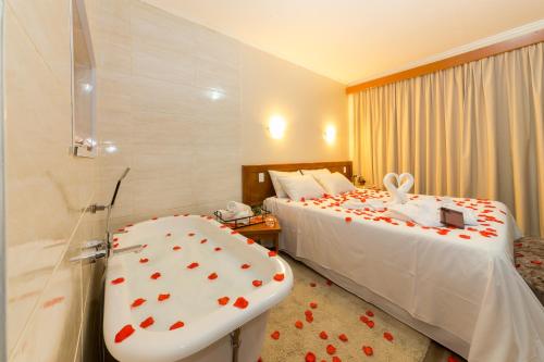 a hotel room with a bed and a bathtub with hearts on it at Hotel Nacional Inn Campos do Jordão in Campos do Jordão
