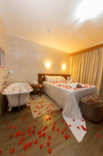 a hotel room with two beds and a bathtub and flowers at Hotel Nacional Inn Campos do Jordão in Campos do Jordão