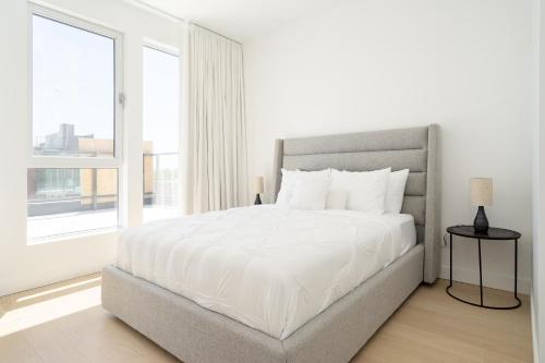 a white bedroom with a large bed and a window at Le Se7t Penthouses in Montréal