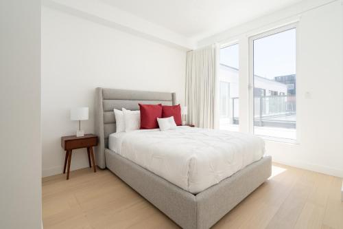 a white bedroom with a large bed with red pillows at Le Se7t Penthouses in Montréal