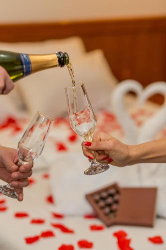 two people are pouring wine into wine glasses at Hotel Nacional Inn Campos do Jordão in Campos do Jordão