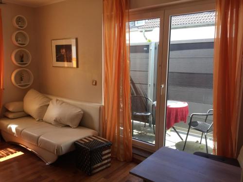 Apartment Leon في بون: غرفة معيشة مع أريكة وباب زجاجي منزلق