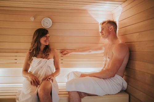 a man and a woman sitting in a sauna at Logis Hôtel de la Tour in Ribeauvillé