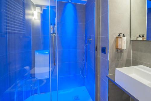 baño azul con ducha y lavamanos en Wellness Home Rome, en Roma