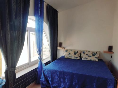 a bedroom with a blue bed and a window at La Torretta di Ognina in Ognina