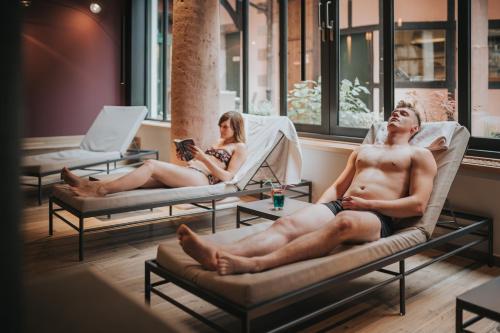 a man and a woman sitting in chairs in a room at Logis Hôtel de la Tour in Ribeauvillé