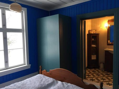 a bedroom with blue walls and a bed and a window at Skjeggestad Gjestehus in Ringebu