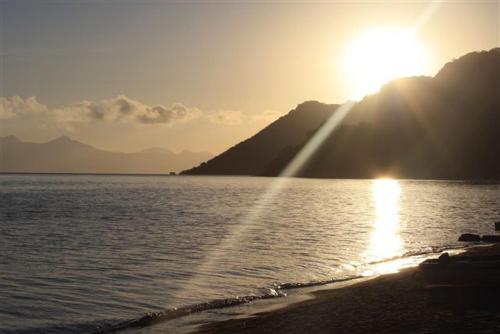 a sun setting over a body of water at Norman Carr Cottage in Monkey Bay