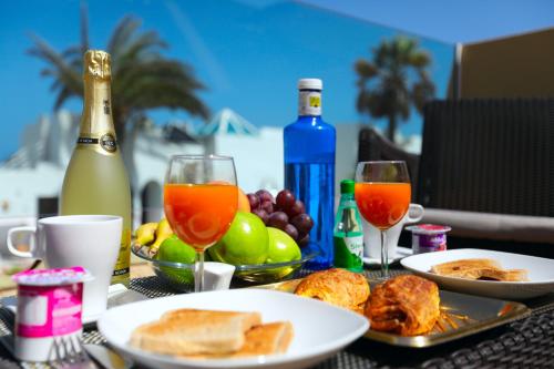 a table with plates of food and two glasses of wine at Apartamentos Fuerteventura Sol in Costa Calma