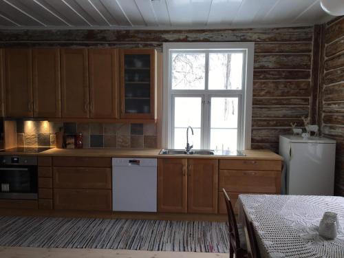 a kitchen with wooden cabinets and a sink and a window at Skjeggestad Gjestehus in Ringebu