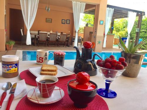 a table with a breakfast of coffee and fruit on it at 4-seasons pool villa near Meteora in Tríkala