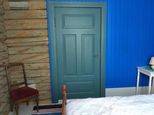 a bedroom with a blue door and a chair at Skjeggestad Gjestehus in Ringebu