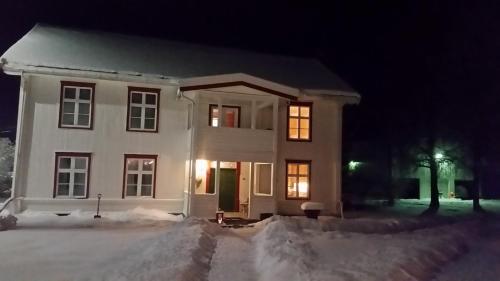 a white house in the snow at night at Skjeggestad Gjestehus in Ringebu