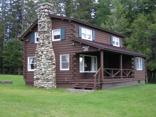 une cabane en rondins avec une cheminée en pierre dans l'établissement Unity Sky Lodge, à Jackman