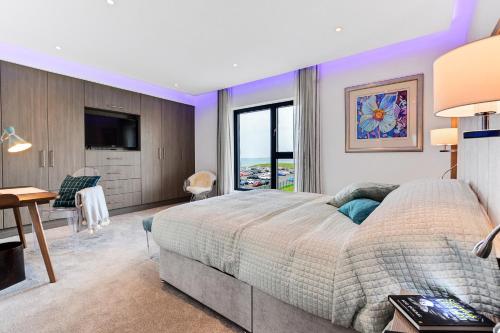 Schlafzimmer mit einem Bett, einem Schreibtisch und einem TV in der Unterkunft Curran Gate Luxury Serviced Apartments, Portrush in Portrush