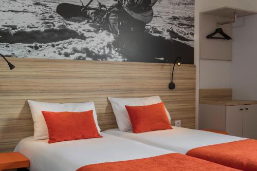 a bedroom with a bed with orange and white pillows at Aka Lodge Lyon Eurexpo Arena Stadium in Meyzieu