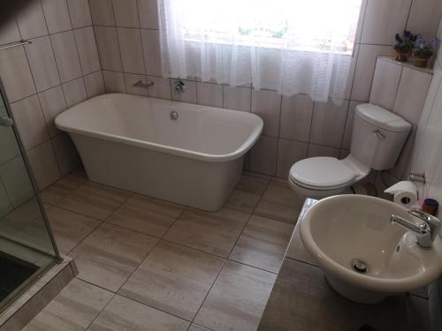 a bathroom with a tub and a toilet and a sink at Windsor Cottage in Barberton