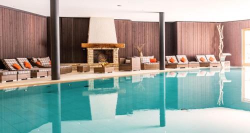 a swimming pool with a fireplace in a hotel room at Chalet RoyAlp Hôtel & Spa in Villars-sur-Ollon