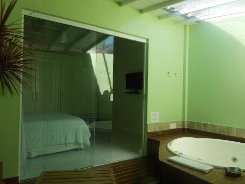 a bathroom with a glass shower and a tub at Pousada dos Reis in Búzios