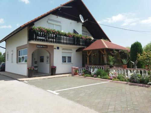 ein weißes Haus mit einem Balkon und einem Parkplatz in der Unterkunft Guesthouse Tomas in Čatrnja