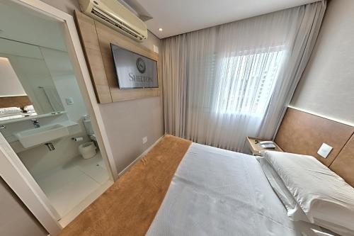 a bedroom with a large bed and a bathroom at Hotel Shelton in Serra Negra
