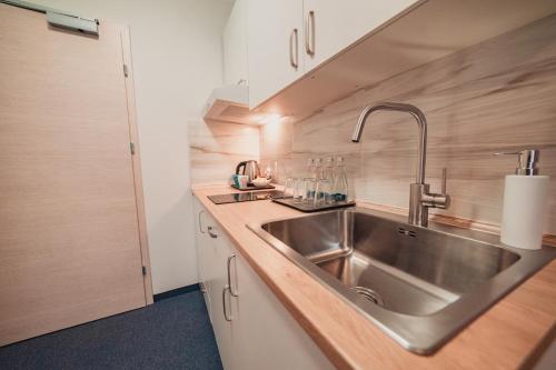 a kitchen with a stainless steel sink and white cabinets at Villa Centro in Oświęcim