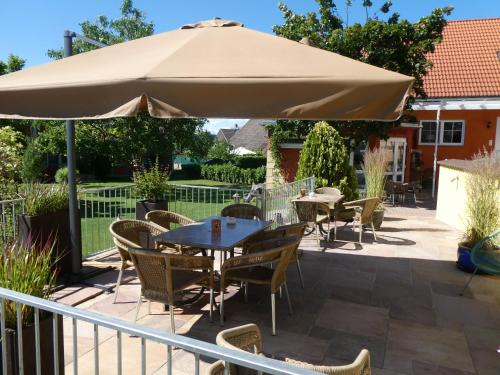 a patio with a table and chairs under a large umbrella at Hotel & Gästehaus Im Ziegelweg KLIMATISIERT Eintrittskarten für den Europa-Park erhalten Sie garantiert über uns in Rust