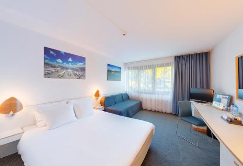 a hotel room with a bed and a desk at Novotel Poznań Malta in Poznań
