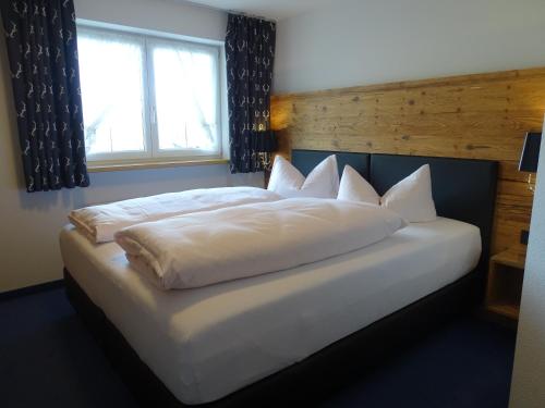 a large white bed in a bedroom with a window at Der Berghof in Hirschegg