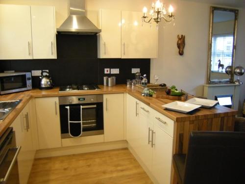 a kitchen with white cabinets and a stove top oven at Knights Rest Conwy Town 5 Star in Conwy