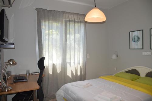 a bedroom with a bed and a desk and a window at Villa Kristi in Loutrá Elevtherón